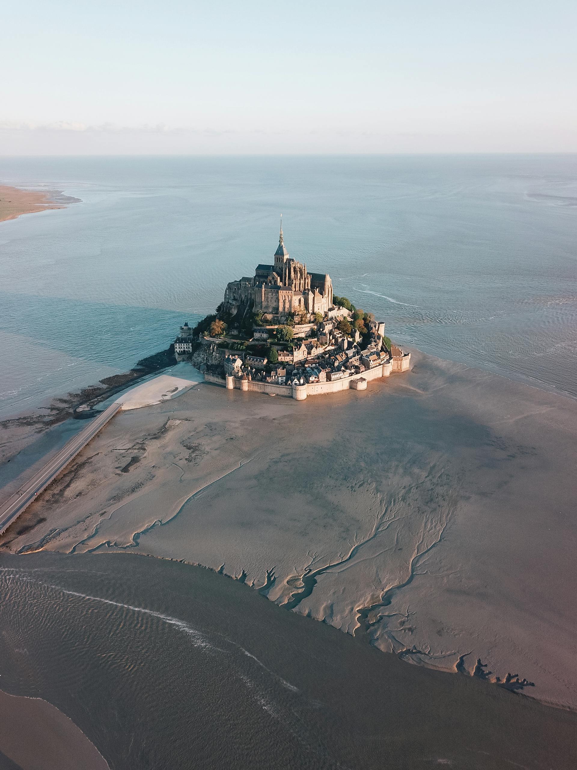 Stunning aerial view of Mont Saint-Michel fortress in France during low tide, surrounded by the vast sea.